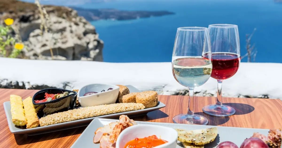 Wine glasses and a meze platter on a terrace above the Santorini caldera at Santo Wines, Pyrgos